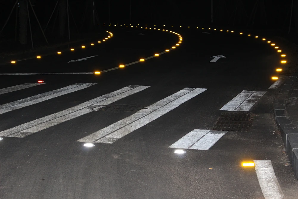 Amber road markers tracing a curved road at night