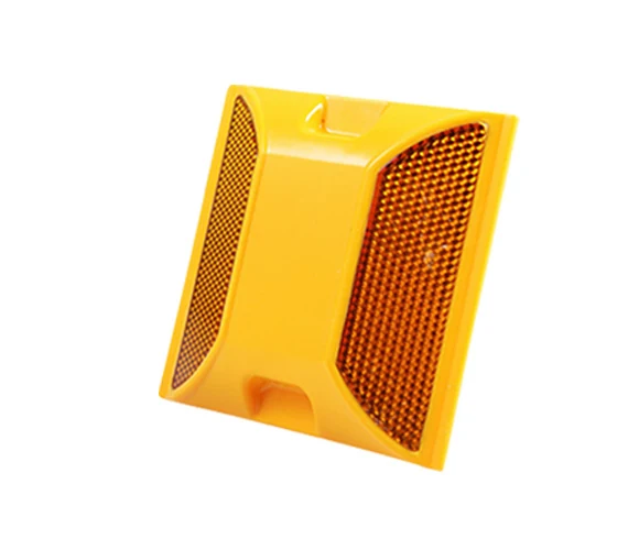 A supplied yellow plastic reflective road stud on a white background